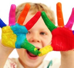 Five year old boy with hands painted in colorful paints ready for hand prints